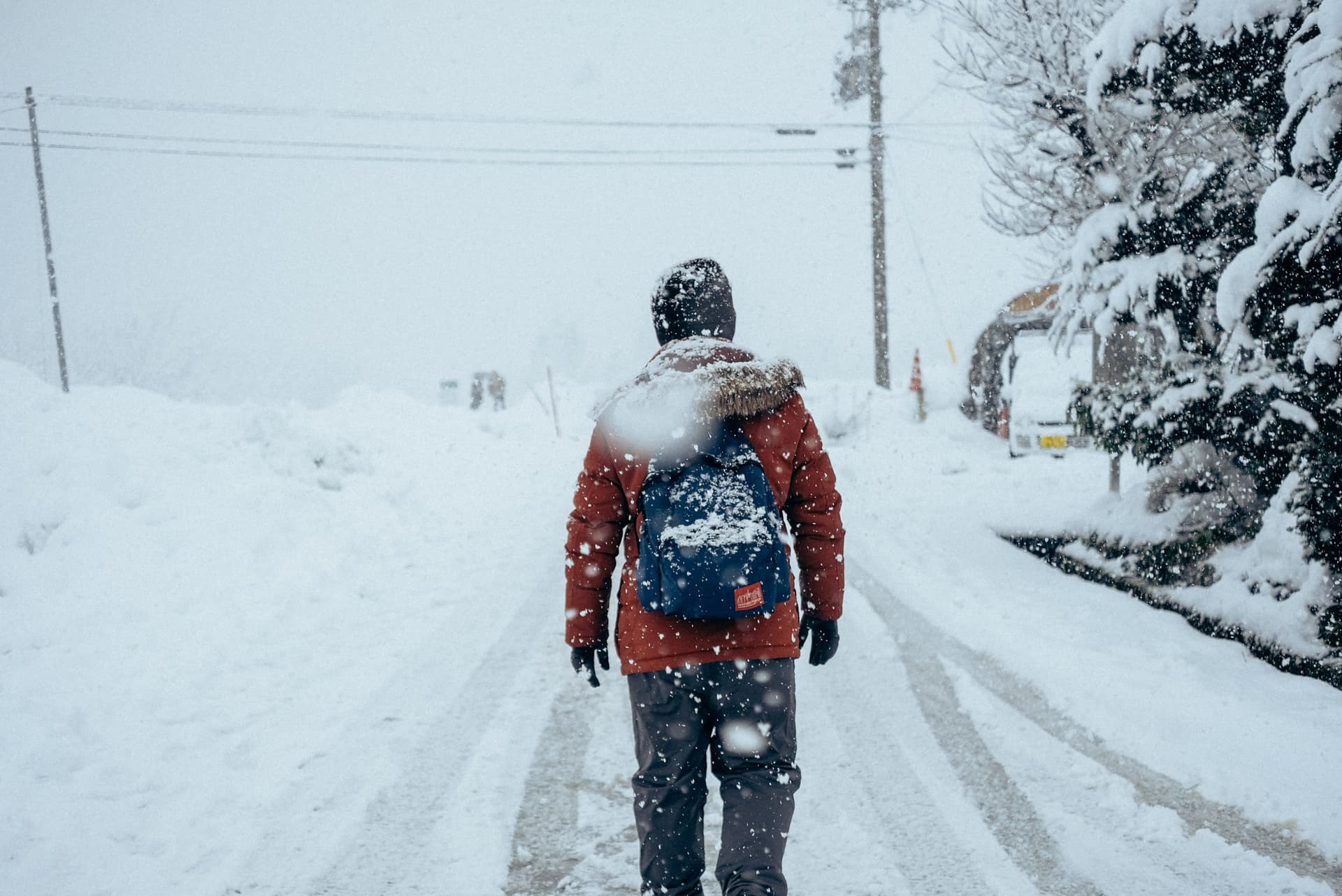 A lone figure walking away down a snowy road